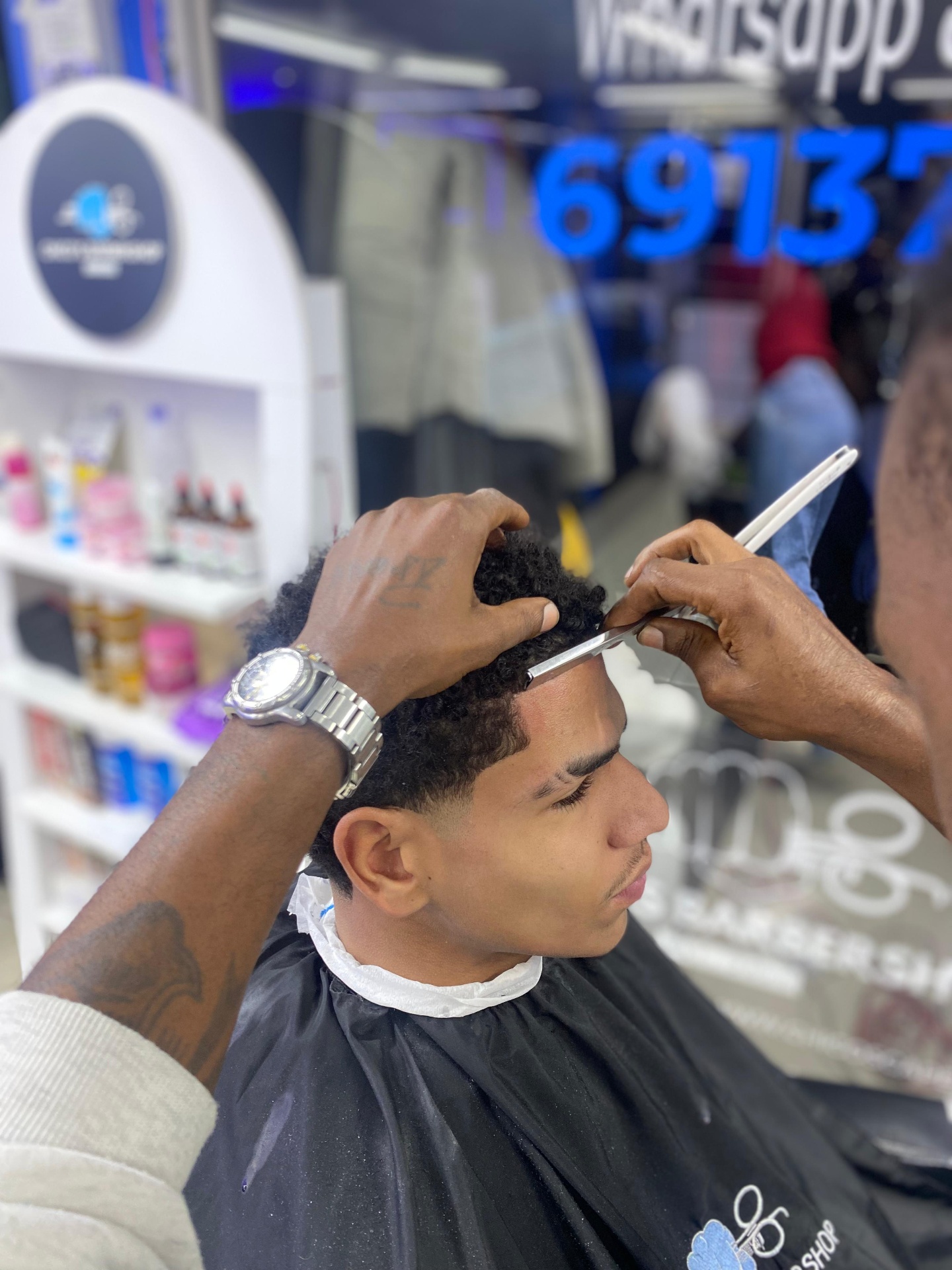 A Chico's barber refining a client's hairline with a razor